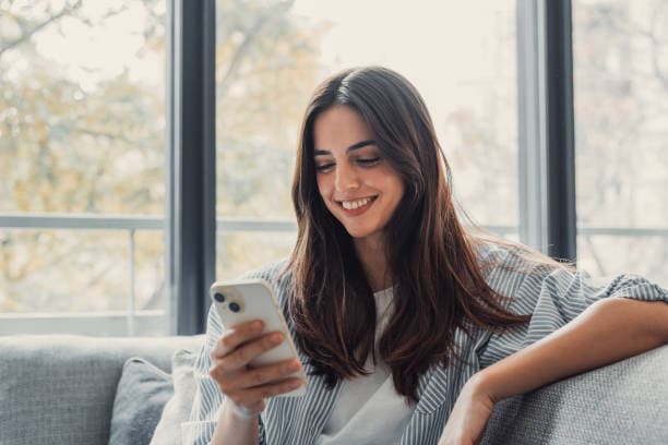Woman smiling at a reward notification on her phone